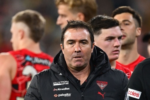 Essendon players walking off the field with heads bowed
